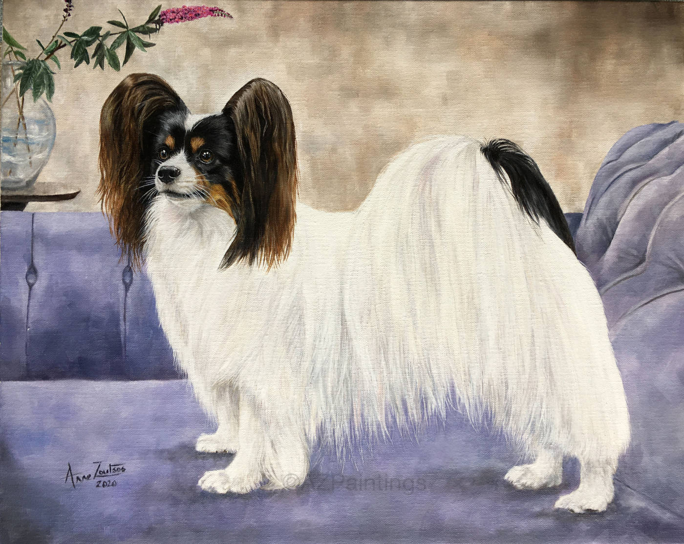 A papillon standing on a chaise longue beside a vase of buddleia
